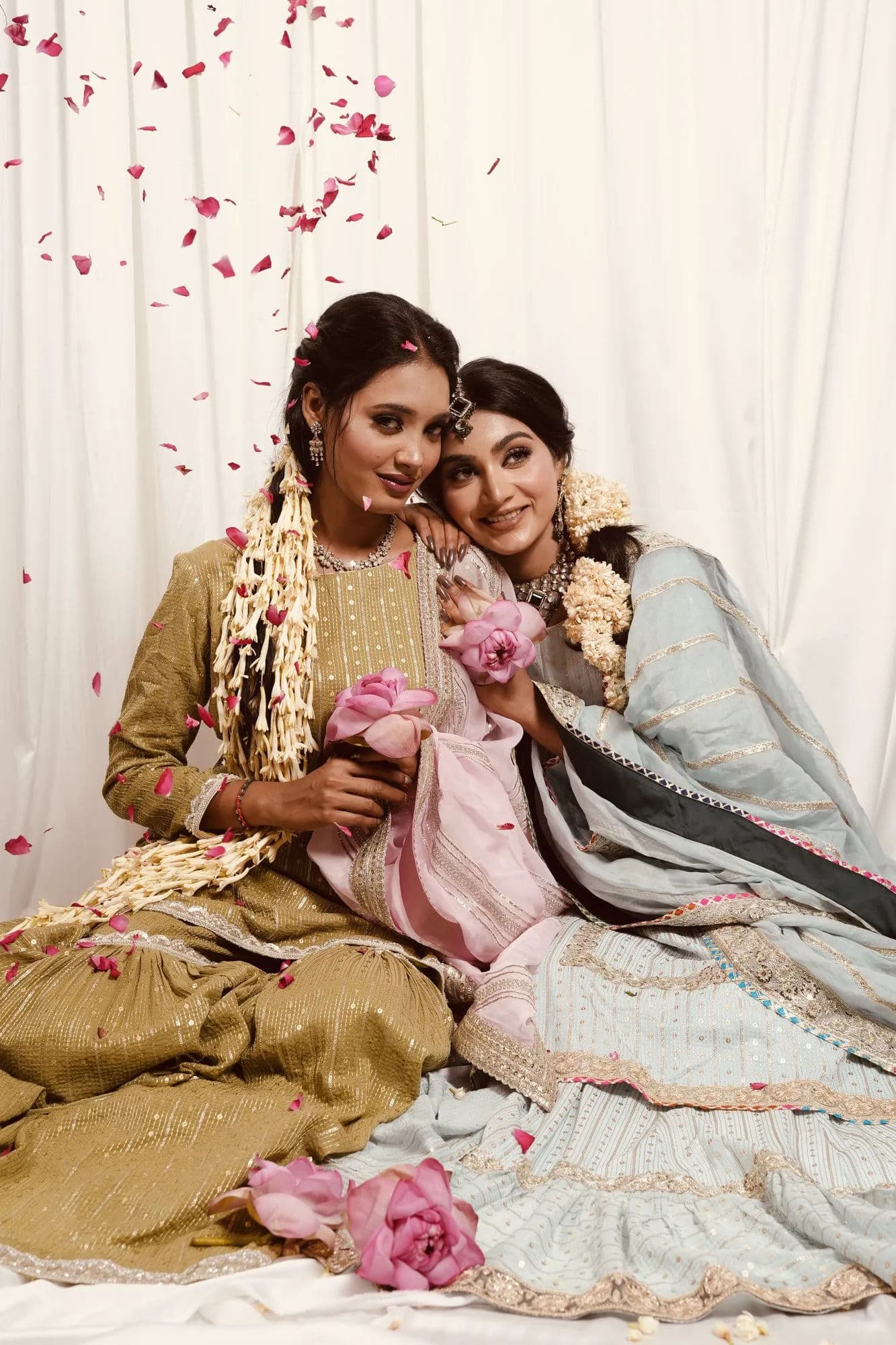 Two guests in festive Sheshri pieces as rose petals fall around them.