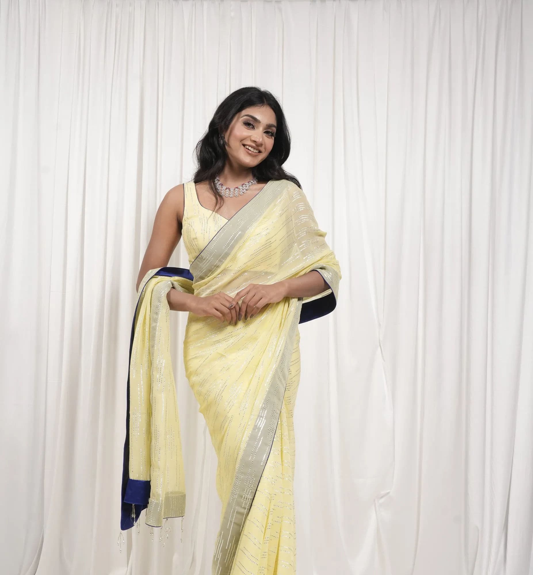 A lemon georgette saree with a silver border and a deep indigo blouse.